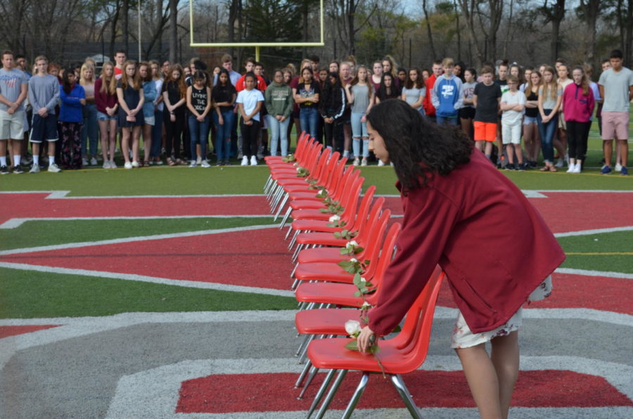 Senior Yasmin Berrada places the last rose, culminating the vigil. Each victim of the shooting had a minute of silence dedicated to their memory. (photo by Maren Kranking)