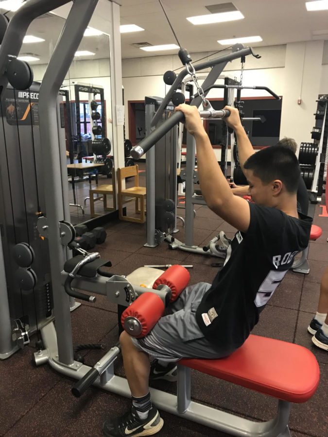 Sophomore Ryan Sim pulls down the bar on the lateral pulldown machine last Monday. It is Sim’s favorite machine.(Photo by Jake Lynes)