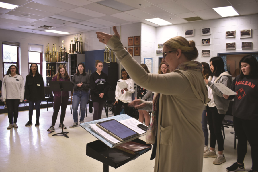 Choir director Linda Martin conducts as choir members practice in preparation for their trip to Iceland. Singers meet to rehearse every Wednesday after school.