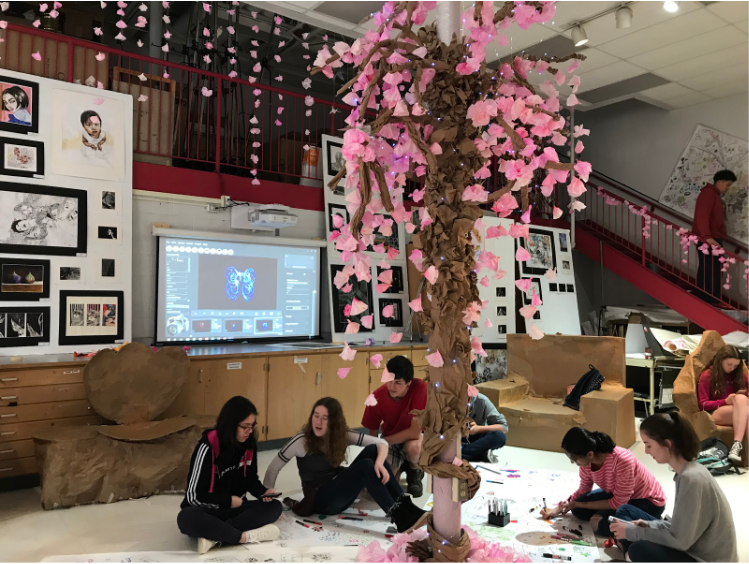 Students sit under the fake cherry blossom tree. They are talking, drawing and enjoying the atmosphere of the gallery. 