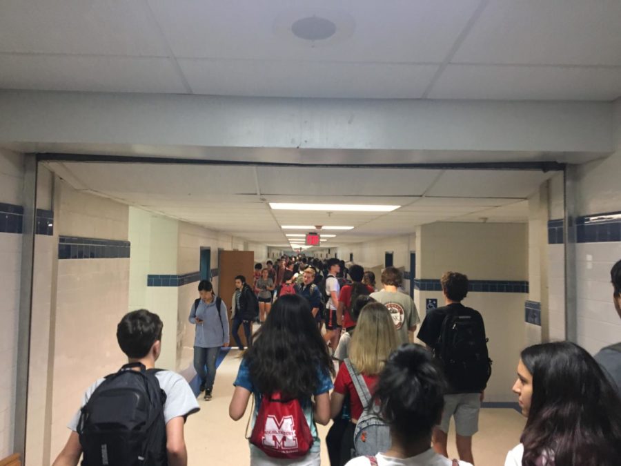 Students pass through the blue hallway during a transition. The flow of people reaches each end of the hallway shoulder to shoulder. Photo by Sebastian Jimenez