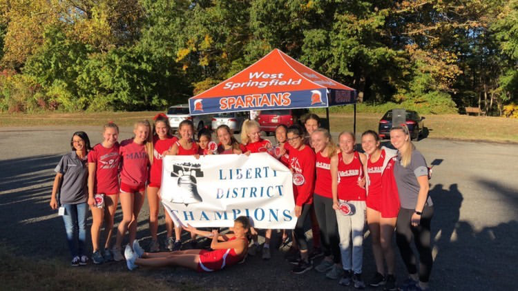 The girls varsity cross country team hols the championship banner