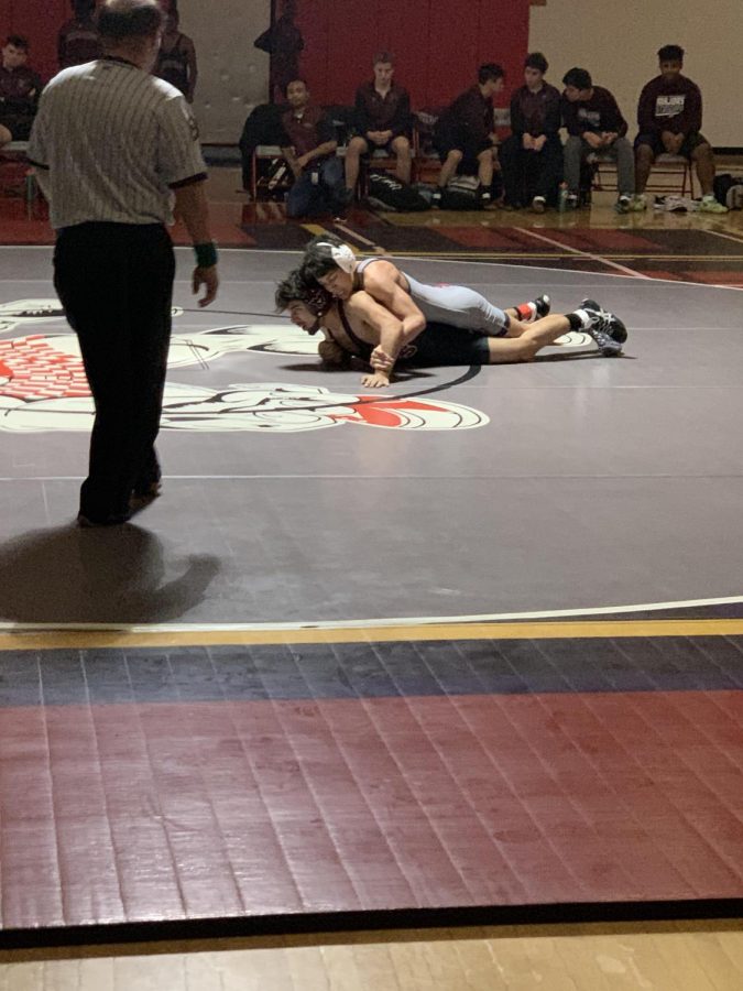 Senior Justin Dehghan secures two points after a take down. These two points were pivotal in the match.