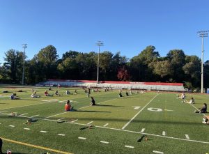 McLean girls field hockey team finishes their practice by stretching. They are spread out across the field in order to maintain social distancing. Photo courtesy of Coach Mary Elizabeth McManus.