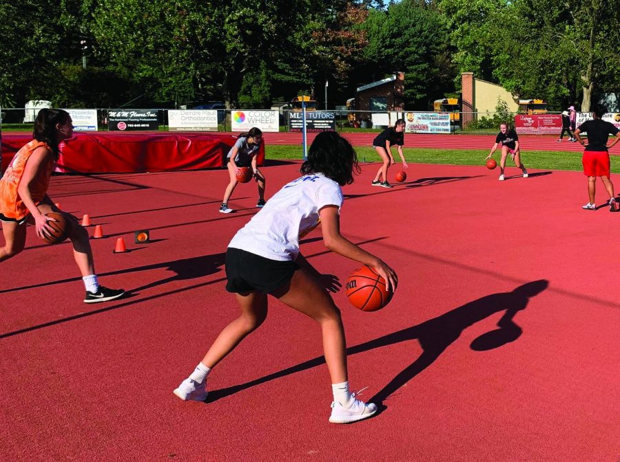 SHADOW ONE-ON-ONE — The girls basketball team begins their Sept. 22 yellow day practice by doing ball handling. Most players have their own balls due to the rule that only two people can touch one ball during the whole practice.