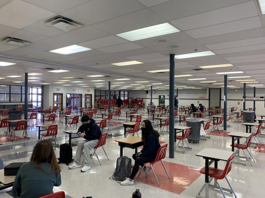 Students eat lunch in the cafeteria. Desks are spaced six feet apart to ensure social distancing.