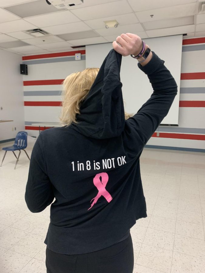 Debbie Feinberg holds up the hood of her shirt to show the statistics that 1 in 8 women will get breast cancer in her lifetime.