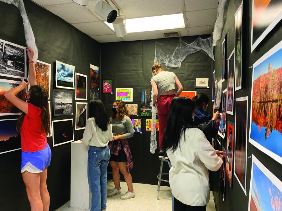 Members of the Art Honor Society work together to hang up students and staff submissions before the Halloween art show.