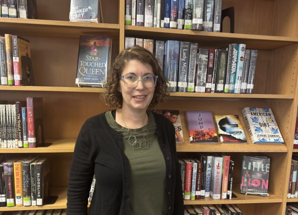 The New Head Librarian, Lish Koch standing next to the newly arranged fiction section.