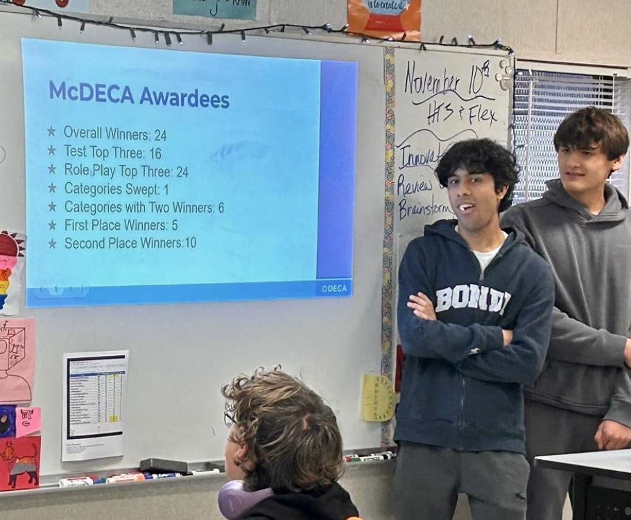 Senior officers Aadil Singh (left) and Nico Christofferson (right) announce district results in DECA meeting.