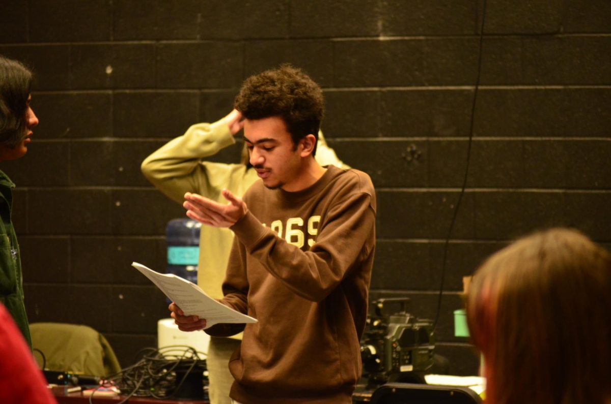 Senior Rafik Hanna rehearses for his lead role in The Cards of Fate playing game show host Buffy