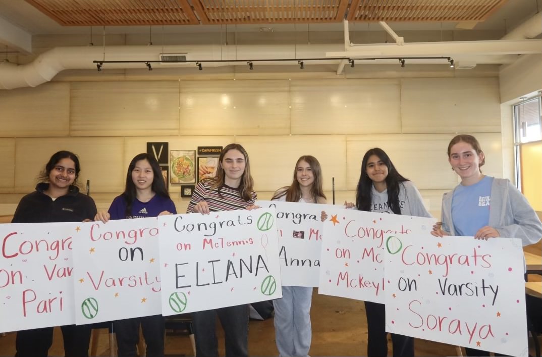 The six new varsity team members hold up their welcome posters. The tennis team is focusing on team bonding and close connections this year.