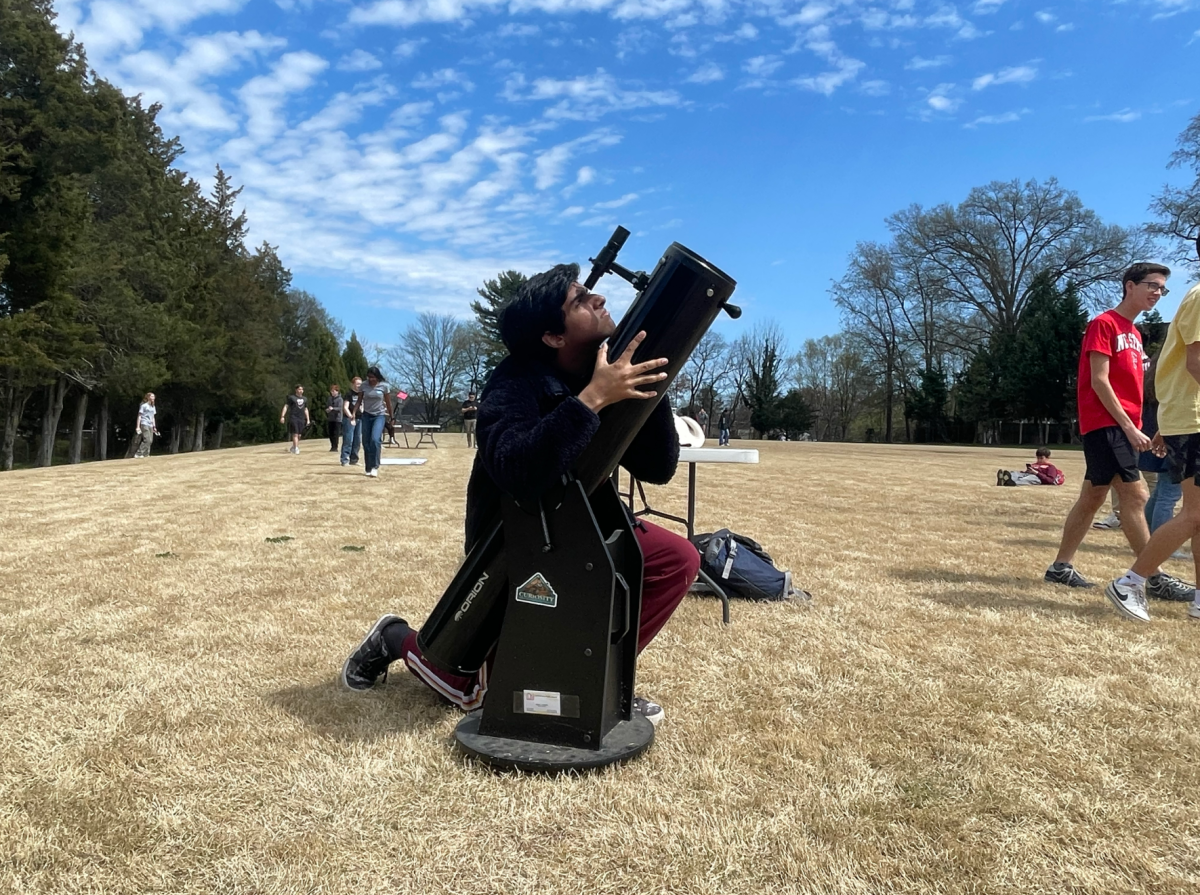 Senior astronomy club member Ishaan Gurazada views the eclipse through a mounted telescope. Professional telescopes require extensive configuration to locate the sun.