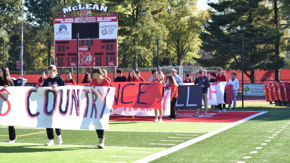 Team captains holding banners representing their sport make their way down the football field during the pep rally on Oct. 18. McLean offers cheer, cross country, dance, field hockey, football, golf and volleyball as fall sports. 

