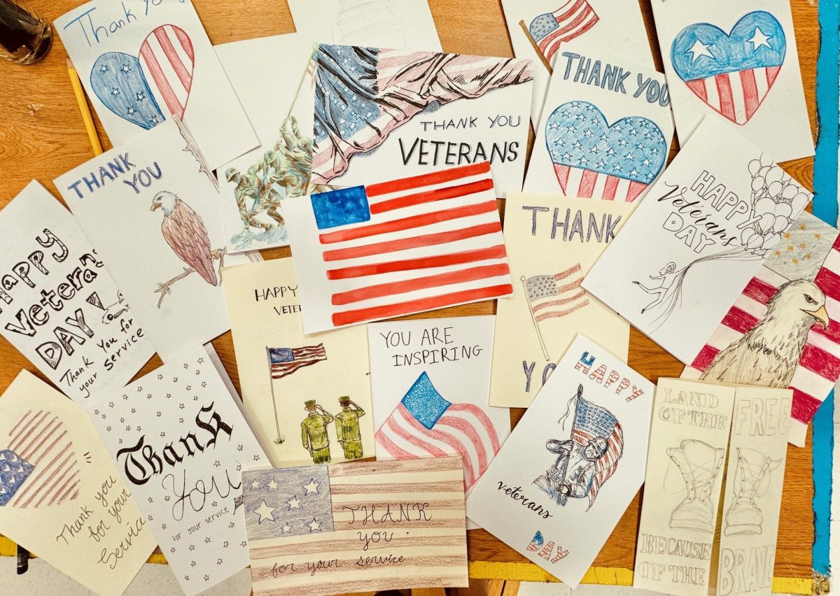 Cards decorated with American flags and classic symbols associated with the United States scatter atop a table. In preparation for Veteran's Day, NAHS students gathered to create cards to honor Americans who have served the nation.