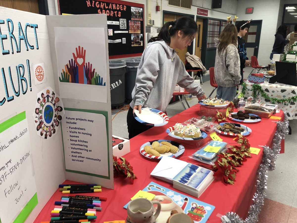 Chloe Jeong, president of the club, sets up different baked goods and festive products for their booth. McLean Interact Club uses Holiday Bazaar as an opportunity to promote their club.