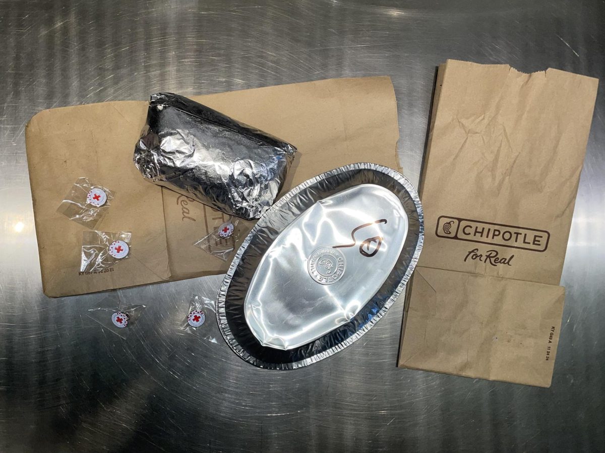 Chipotle meals next to the Red Cross pins are a partnership for global health. Every bite helps fund vaccines for underserved communities through the 'Vaccinate a Village' campaign.