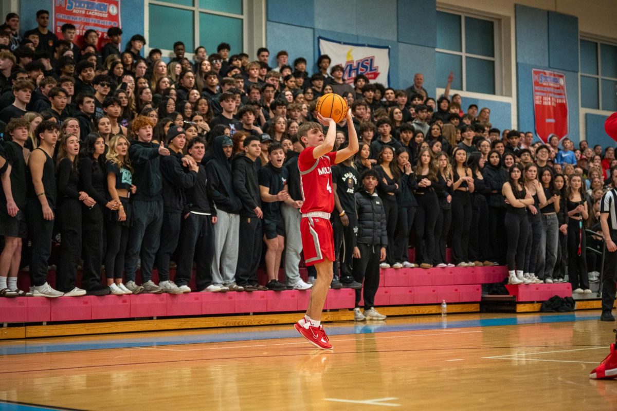 Junior Nickolaos Karageorgos takes an open shot from behind the three point line in front of the imposing Marshall student section.