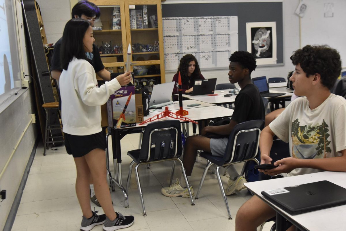 Sophomore Eunice Sim, founder and president of the Rocketry Club, shows club members sample rockets. Sim is preparing the team for the American Rocketry Challenge this year. 