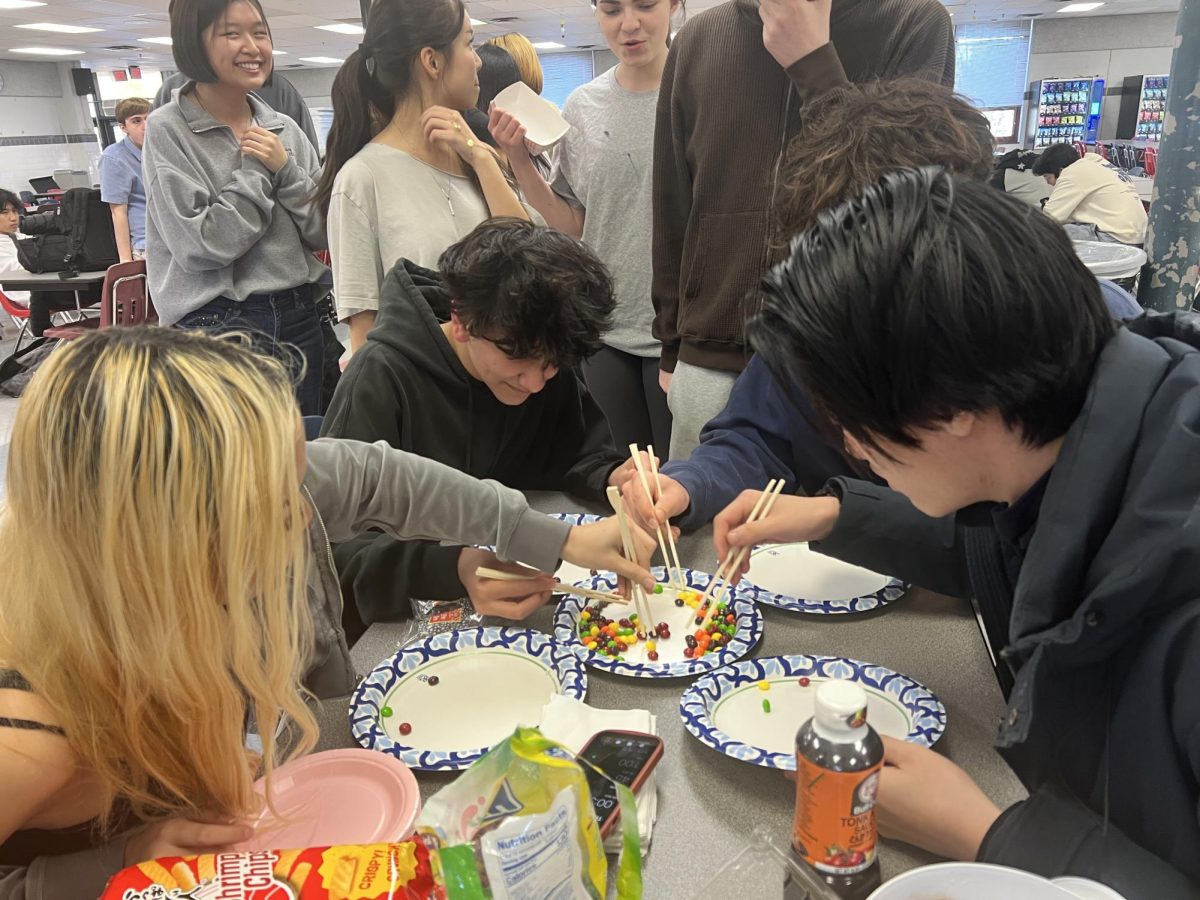 Students use chopsticks to try to grab as many Skittles as possible to win the game.