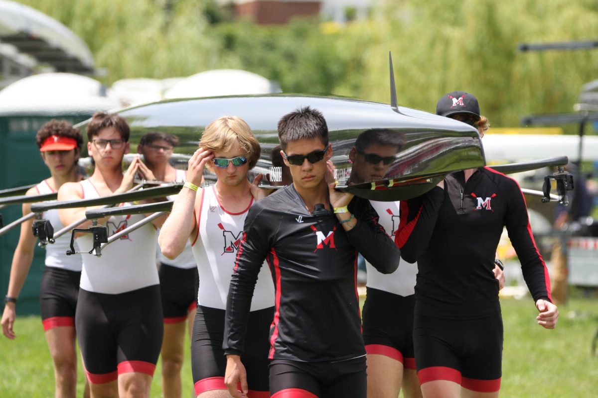 Junior Carson Fast (front) carries the 1V boat to the water at the 2025 Canadian Secondary School Regatta at St. Catharines, Canada. The boat placed third overall.