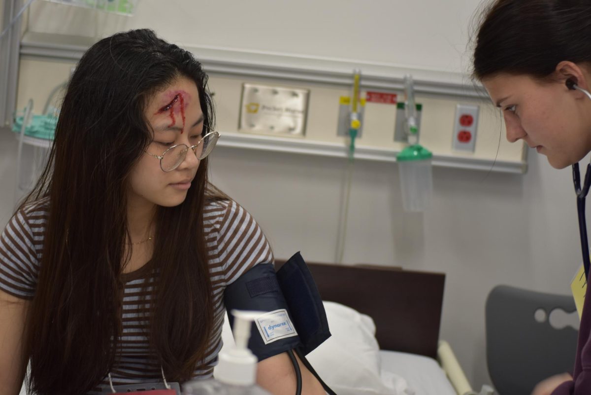 Student assessing blood pressure of simulated victim.