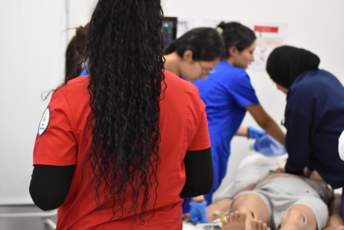 Students giving CPR to manikin representing victim.