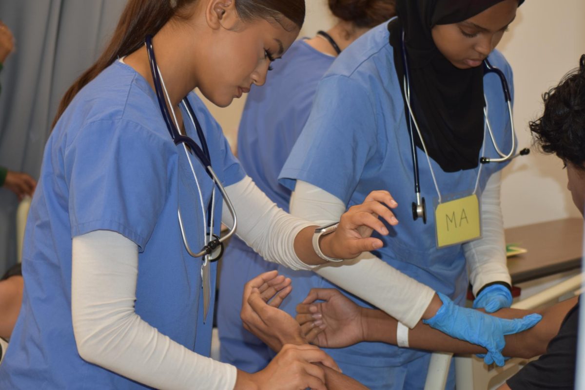 Medical assistants taking vitals of patient.